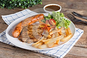 Roasted beef meat steak and sausage with french fries.