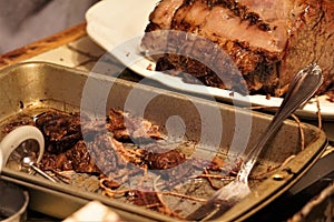 Roasted beef on platter next to fatty bits and string in pan