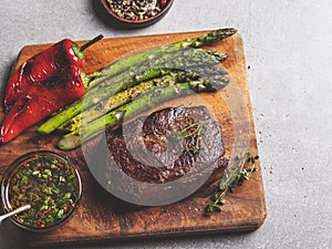 roasted beef steak, mutton with asparagus pepper on a cutting board, sauce with olive oil and herbs, spices