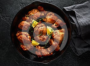 Roasted boneless skinless chicken thighs in lemon and thyme dressing served in vintage cast iron skillet, frying pan