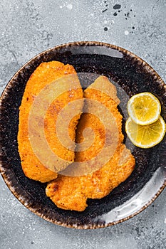 Roasted breaded german weiner schnitzel on a plate. Gray background. Top view