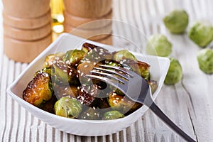 Roasted Brussels sprouts in a white bowl on a wooden background