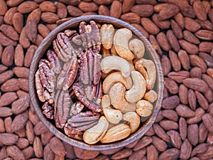 Roasted cashew, pecans and almonds in and around a wooden bowl
