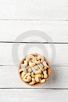 Roasted cashews in bowl on white wooden table.