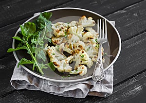 Roasted cauliflower and fresh arugula on a brown plate