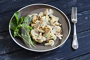 Roasted cauliflower and fresh green salad on a brown plate