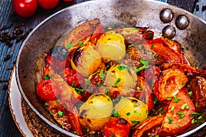 Roasted cherry tomatoes in cast iron skillet on wooden table