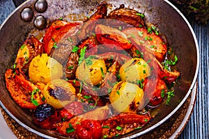 Roasted cherry tomatoes in cast iron skillet on wooden table