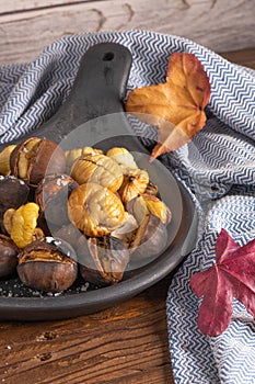 Roasted chestnuts in cast iron pan on an old board