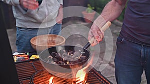 Roasted chestnuts and maroni over the fire in a special steel pan. Traditional Italian autumn delicacies