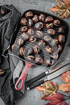 Roasted chestnuts served in chestnut pan on an old table.