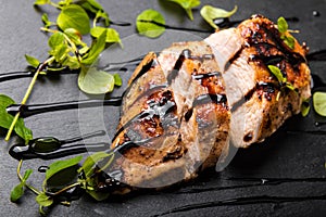 Roasted Chicken Breast on a Black Stone Plate with Balsamic Vinegar and Oregano