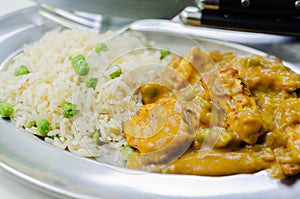Roasted chicken breast pieces in a mildly spiced coconut curry sauce with fried rice with peas and egg
