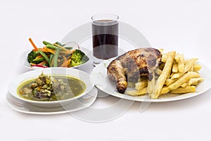 Roasted chicken leg with fries potato called Pollo a la Brasa. Menu served with fresh salad, chicken soup of coriander
