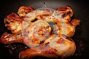 Roasted chicken legs in a black pan