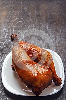 Roasted chicken legs cooked on a barbecue on a white plate on a black background. Top view from above. Copy space