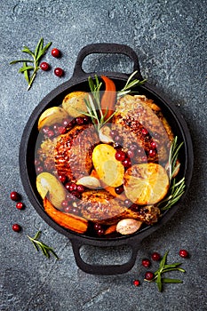 Roasted chicken legs with root vegetables, lemon, garlic, cranberry and rosemary on pan