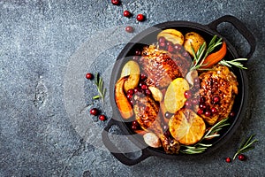 Roasted chicken legs with root vegetables, lemon, garlic, cranberry and rosemary on pan