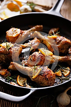 Roasted chicken legs with rosemary, garlic and lemon in a cast iron skillet