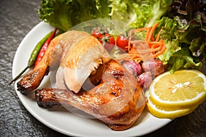 Roasted chicken legs white plate with lemon chilli spicy herbs spices and salad lettuce vegetable