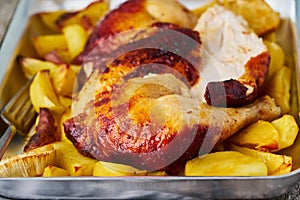 Roasted chicken meat, leg, thigh with baked potatoes. Side view, close up