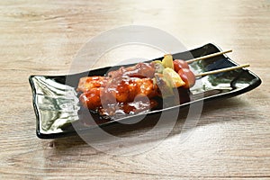 Roasted chicken with pineapple chili and tomato dressing barbecue sauce stabbing wooden stick on plate