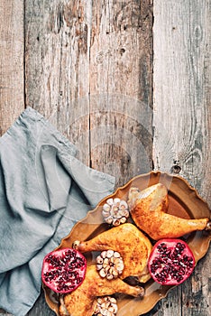 Roasted chicken with pomegranate and garlic on wooden background. Friends or family dinner. Festive Christmas table. Top view.