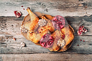 Roasted chicken with pomegranate and garlic on wooden background. Friends or family dinner. Festive Christmas table. Top view.