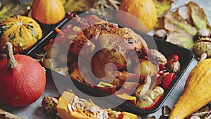 Roasted chicken or turkey garnished with pumpkins, pepper and potatoes. Served on a rustic table