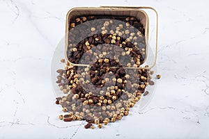 Roasted chickpea and raisins mix in a basket, scatchered around basket nuts, turkish style snack