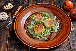 Roasted chickpeas falafel patties with arugula on a plate. Dark wooden background. Top view