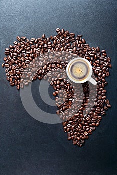 Roasted coffe beans shaping Map of the Africa on blackboard with cup of coffee