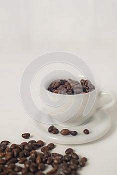 Roasted coffee bean in a cup against white background