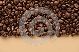 Roasted coffee beans on beige background with copy space. Close up top view.