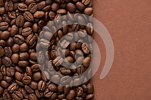 Roasted coffee beans on brown background with copy space. Close up top view.