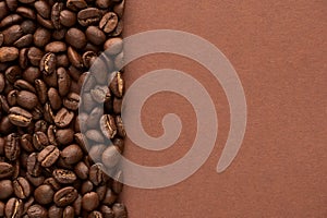 Roasted coffee beans on brown background with copy space. Close up top view