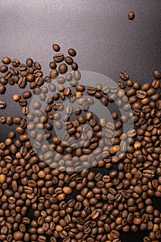 Roasted coffee beans in bulk on a black background. dark cofee roasted grain flavor aroma cafe, natural coffe shop background, top