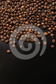 Roasted coffee beans in bulk on a black background. dark cofee roasted grain flavor aroma cafe, natural coffe shop background, top