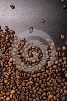 Roasted coffee beans in bulk on a black background. dark cofee roasted grain flavor aroma cafe, natural coffe shop background, top