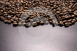 Roasted coffee beans in bulk on a black background. dark cofee roasted grain flavor aroma cafe, natural coffe shop background, top