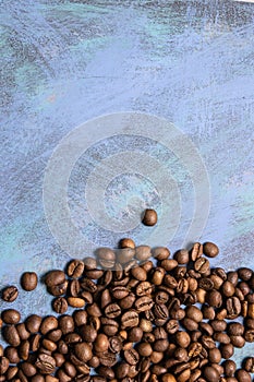 Roasted coffee beans in bulk on a blue background. dark cofee roasted grain flavor aroma cafe, natural coffe shop background, top