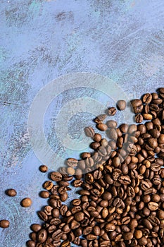 Roasted coffee beans in bulk on a blue background. dark cofee roasted grain flavor aroma cafe, natural coffe shop background, top