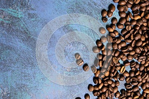 Roasted coffee beans in bulk on a blue background. dark cofee roasted grain flavor aroma cafe, natural coffe shop background, top