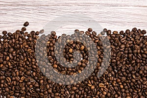 Roasted coffee beans in bulk on a light wooden background. dark cofee roasted grain flavor aroma cafe, natural coffe shop