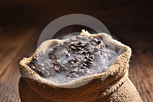 Roasted coffee beans in burlap sack with smoke on top. Freshly roasted strong aromatic dark brown coffee beans with smoke in burla photo