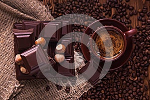 Roasted coffee beans, chocolate, nuts and cup on the wooden background