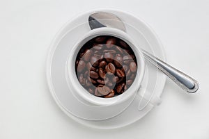 Roasted coffee beans in a coffee cup against white background with space for text, view from above