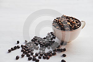 .Roasted coffee beans in a coffee cup on a white table