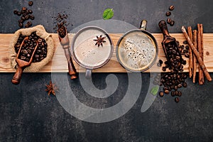 Roasted coffee beans with coffee powder and flavourful ingredients for make tasty coffee setup on dark stone background
