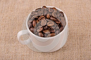 Roasted coffee beans in coffeecup on burlap photo